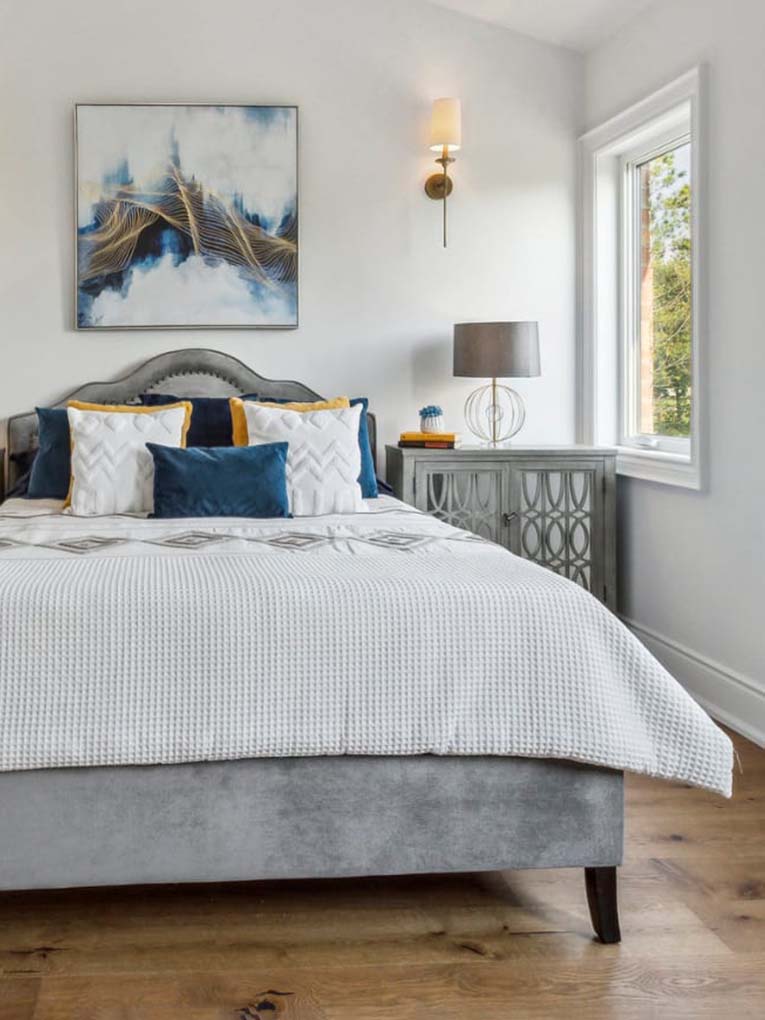 Beautiful bedroom staged for real estate with white and blue bedding and art.