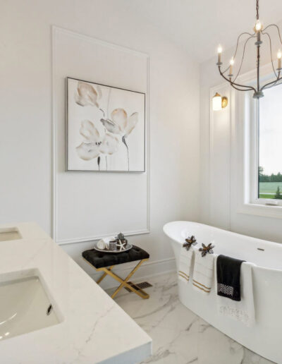Off-bedroom bathroom with white soaker tub, quartz countertop, and gold chandelier.